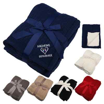 Navy blue cable knit blanket with embroidered design.